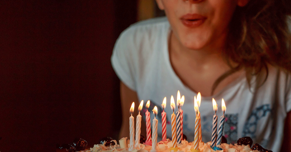 A young girl blowing out candles on a birthday cake.