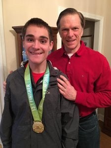 A father and his teenage son who's wearing a medal around his neck