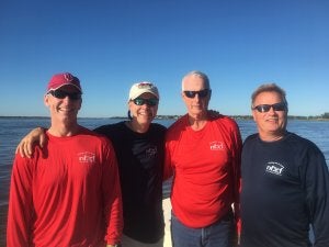 Four adult men standing in front of a large lake