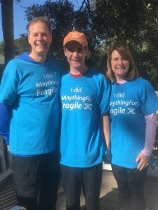 A father, mother, and teenage son wearing matching blue t-shirts that say I did Anything for Fragile X