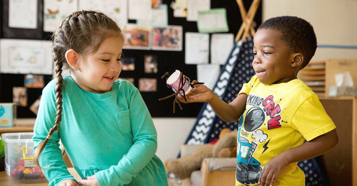 A young girl and boy playing together in classroom.