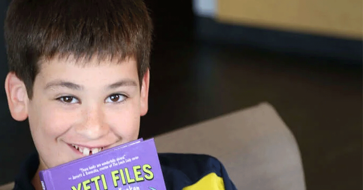 A young boy looking over the top of his open book.
