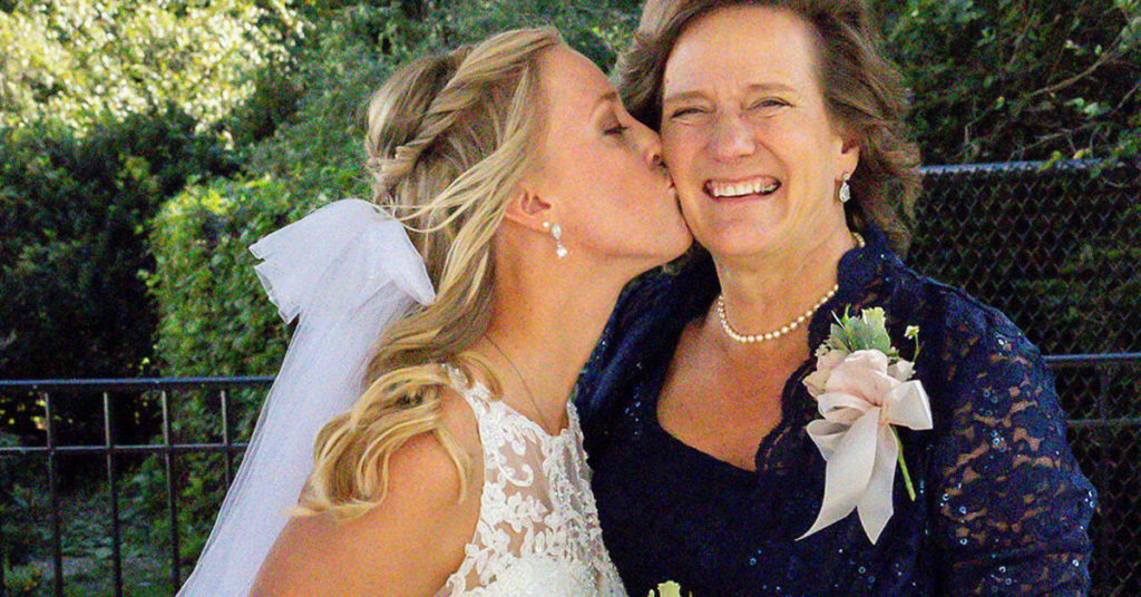 A bride kissing her mother on the cheek.
