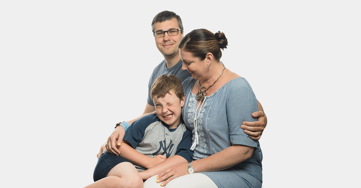 A mother and father hugging their son with Fragile X