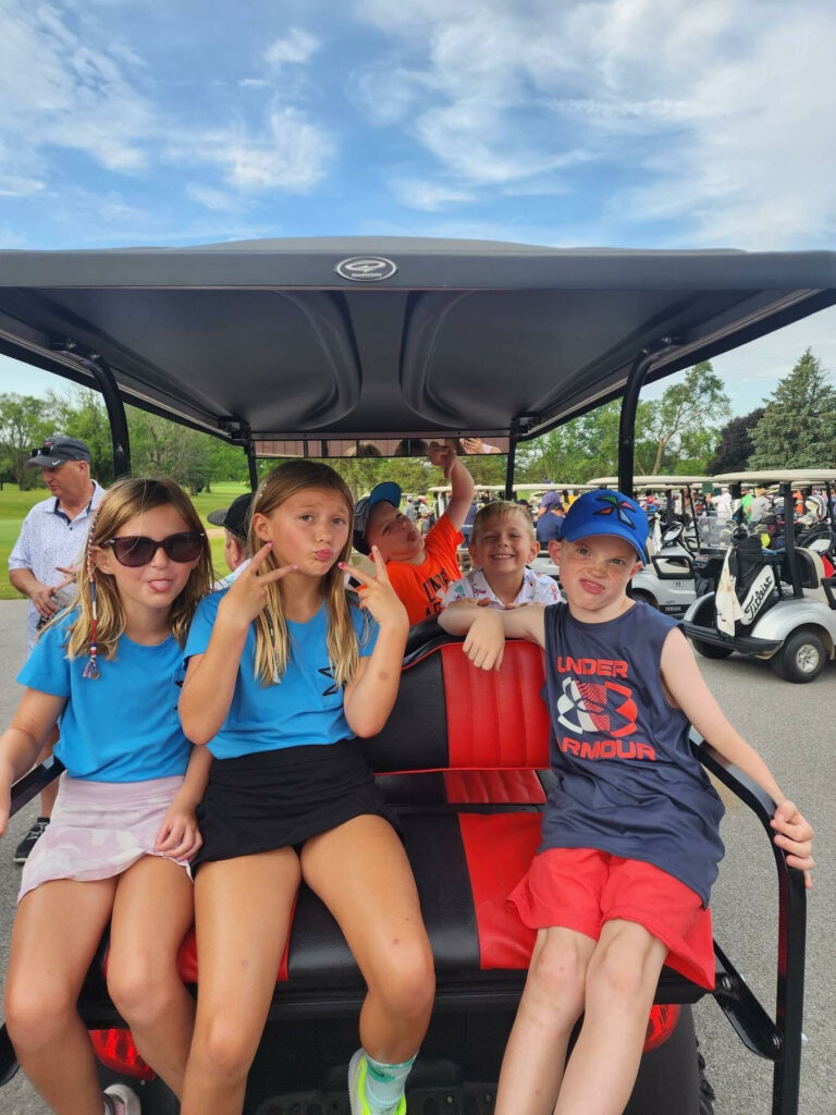 Several children in a golf cart.
