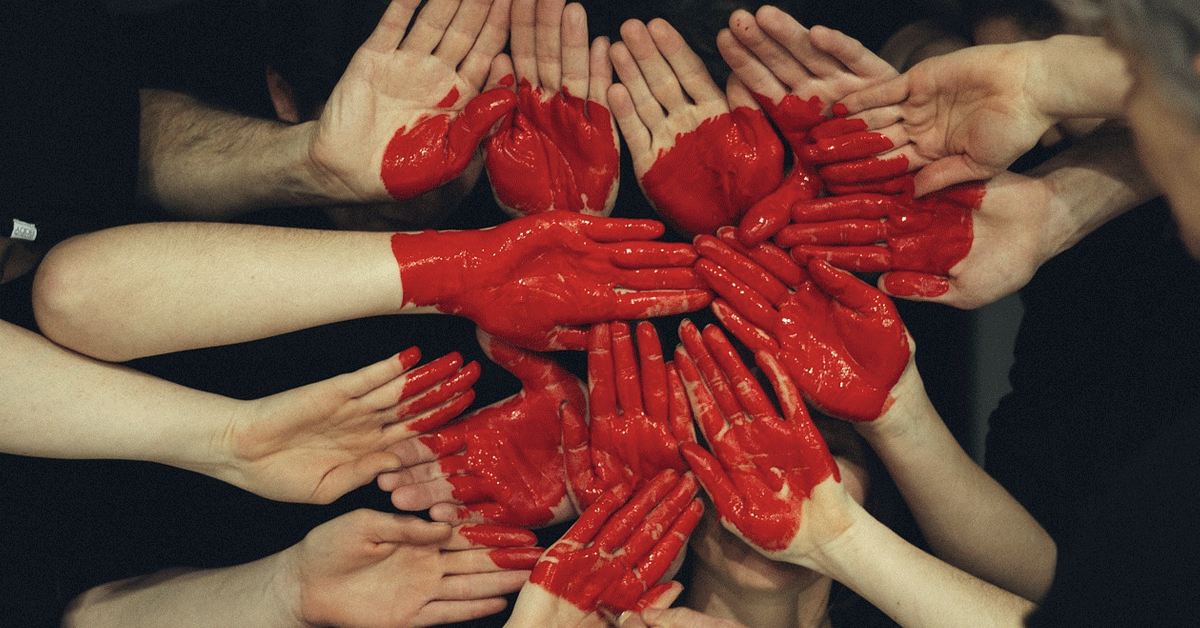 Team hands linked together with heart painted across.