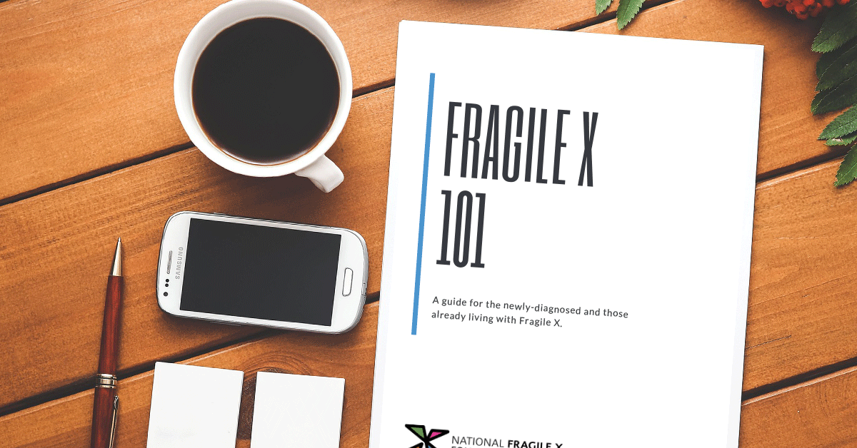 Fragile X 101 ebook on a table with a smartphone and cup of coffee