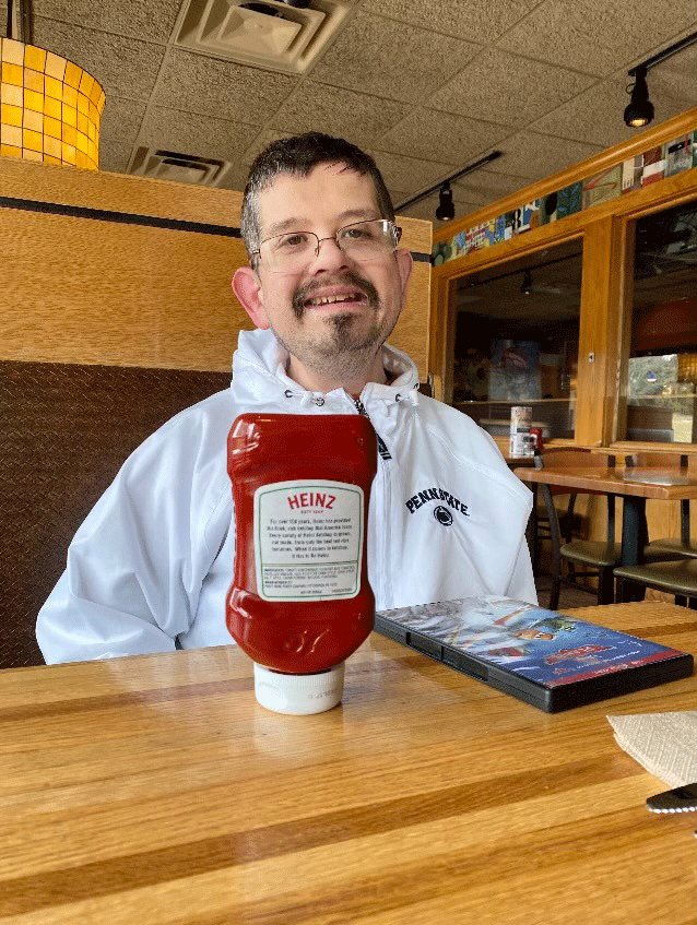 Andrew Pritchard at a dining room table with a bottle of ketchup, which he puts on everything he eats.