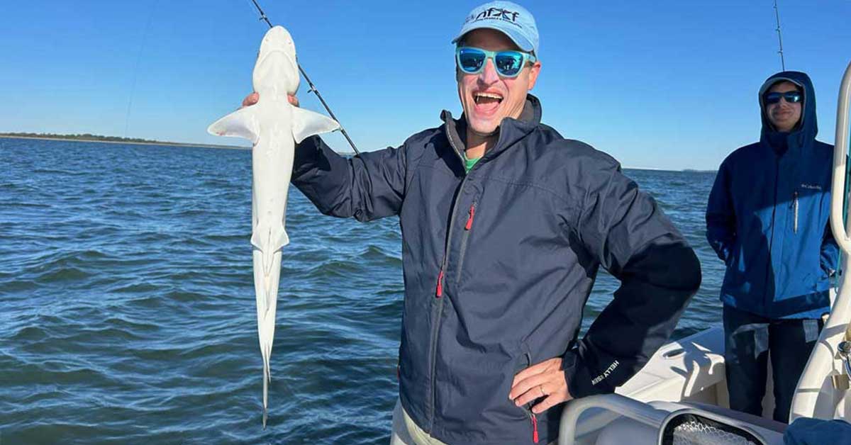 A fisherman at sea holds up his catch.