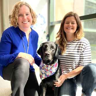 Ann Kjolhaug, MA, CCLS, and Cala Hefferan, MA, CCLS, and their Facility Dog, Jersey.