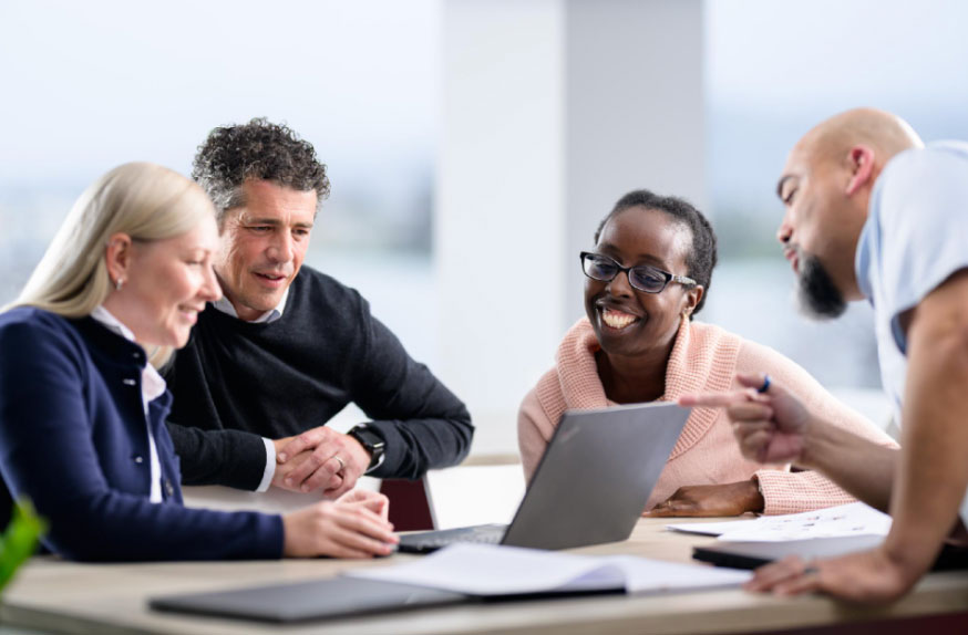 Four people looking at a laptop computer screen and discussing.