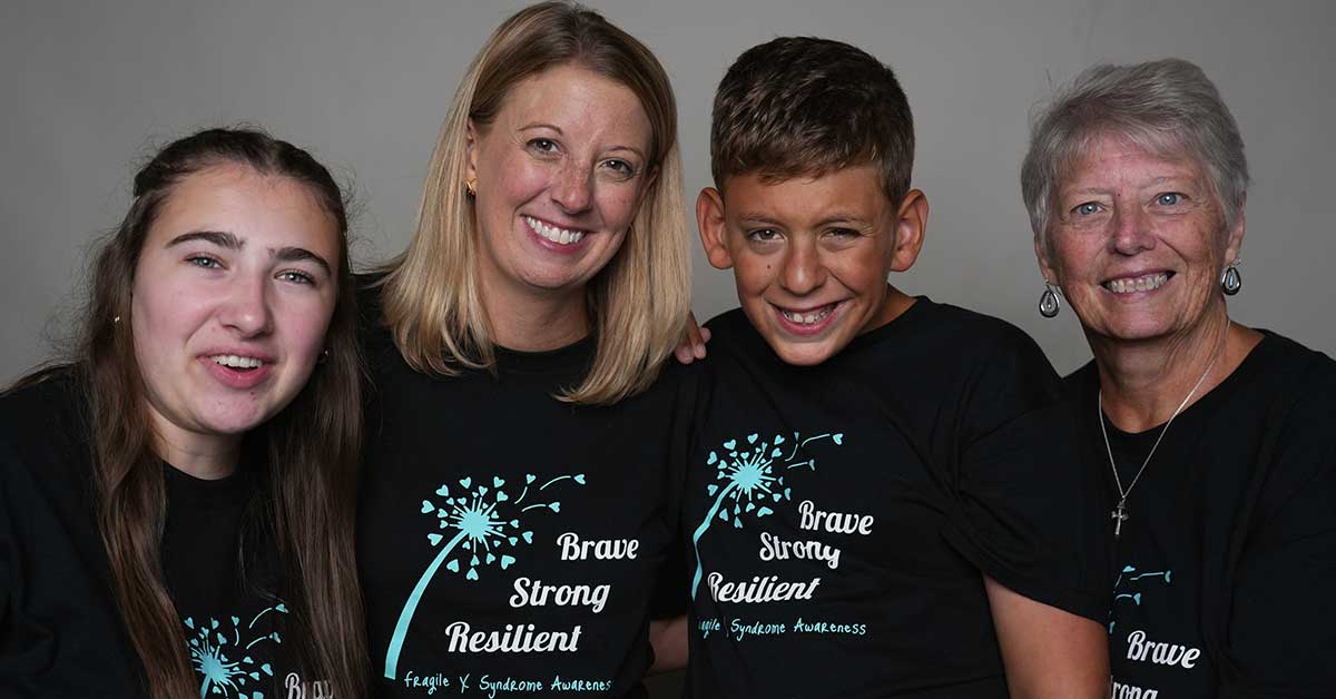 Three generations, Grandmother, Mom, and two teens, at the International Fragile X Conference, wearing matching shirts that say "Brave, Strong, Resilient."