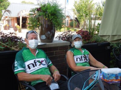 2 participants of the The 5th Annual Bike to X Out Fragile X at a table outdoors.