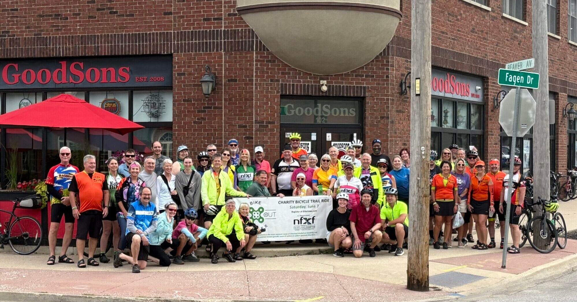 Group of bikers pose on sidewalk
