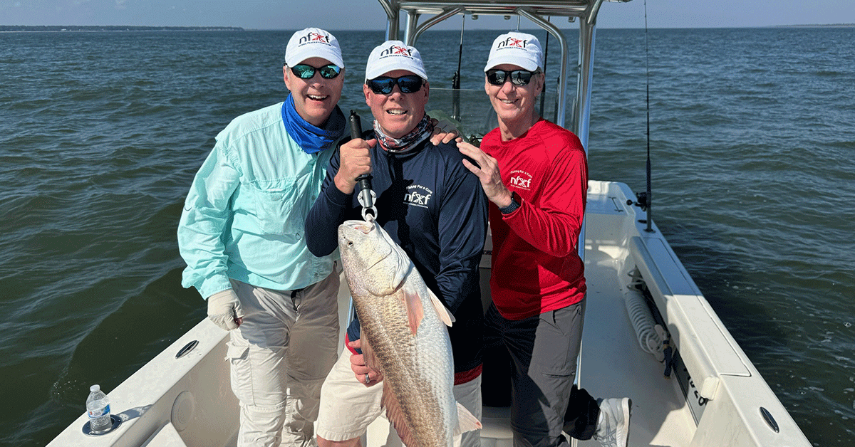 Three fishermen at sea, one with a huge catch still on the hook.