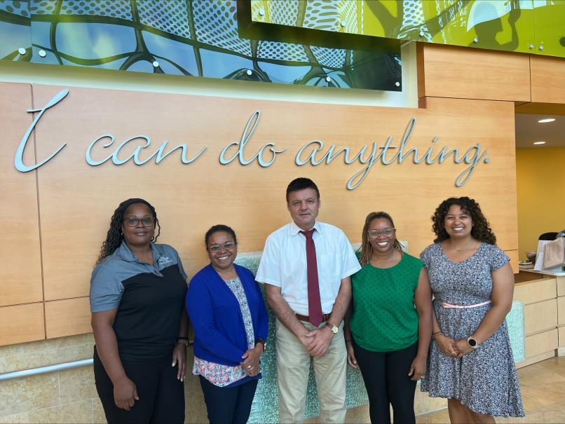 Five individuals standing in front of a sign that says "I can do anything"