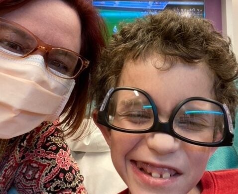 A boy smiling with glasses upside down on his face