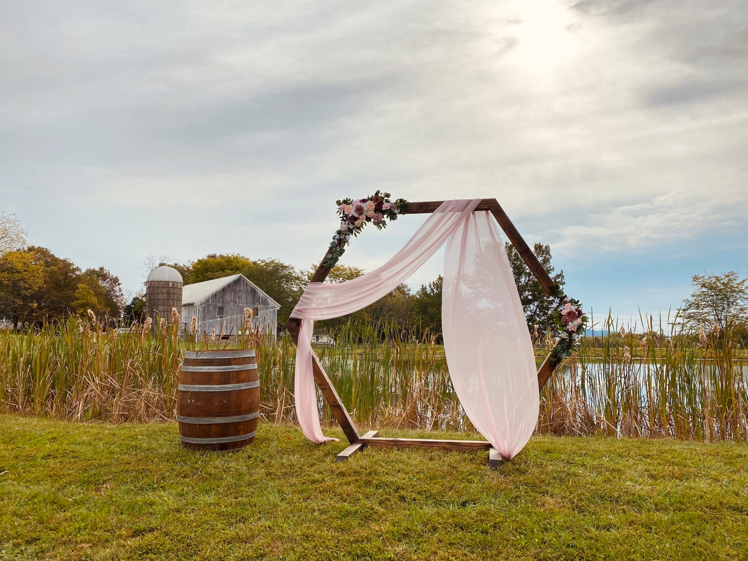 a gazebo and wine barrel in front of a pond