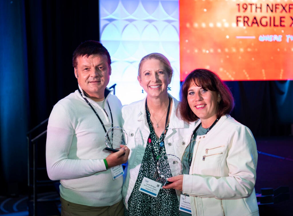 Three people, two holding awards.