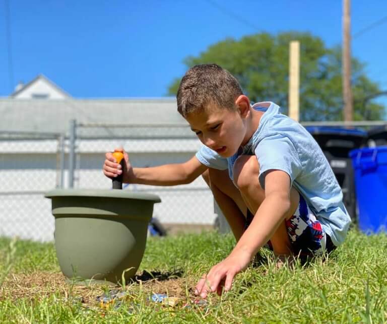 Girius Owen Akkawi outdoors playing in the grass and dirt.