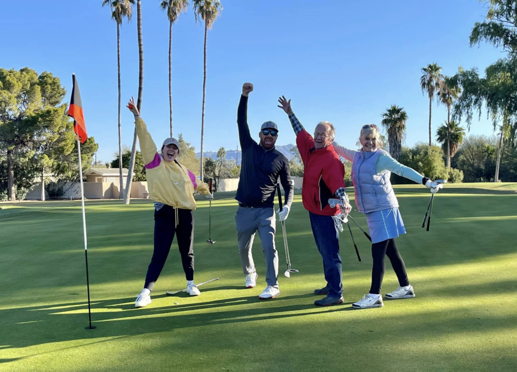 Four golfers jumping and raising their arms