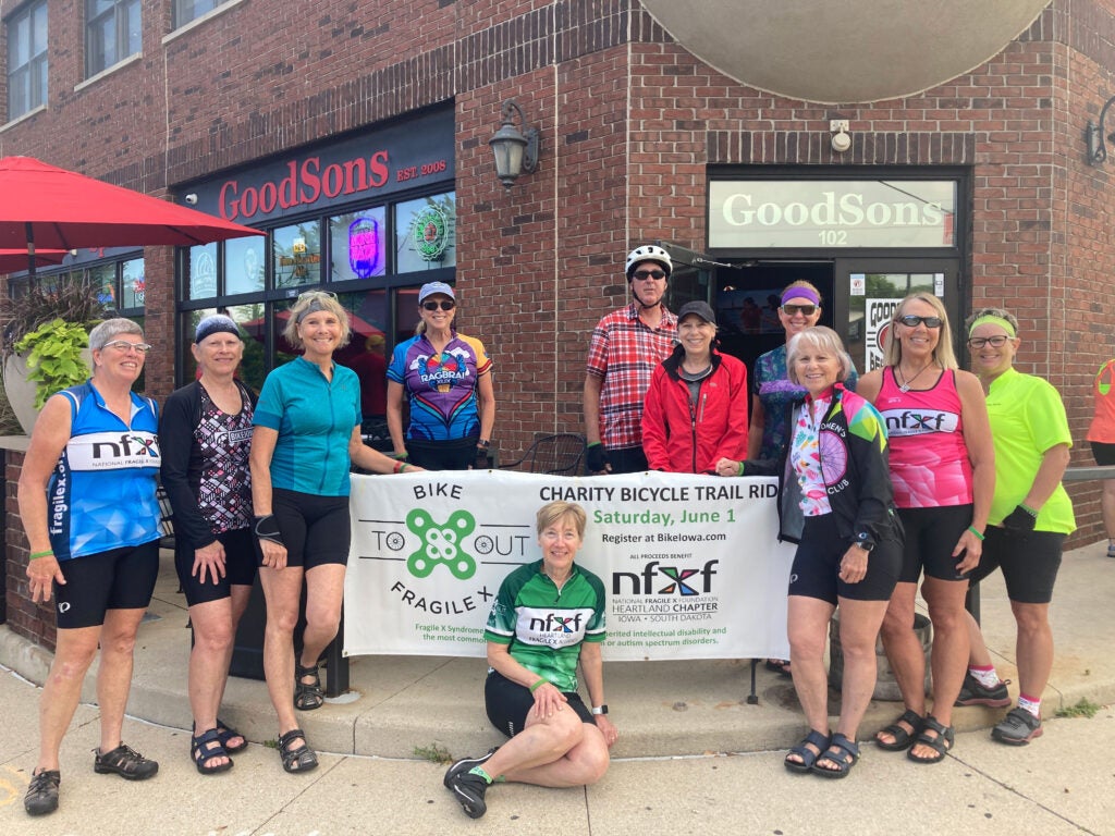 Ride to X Out Fragile X even organizers in front of GoodSons bar with an event banner.