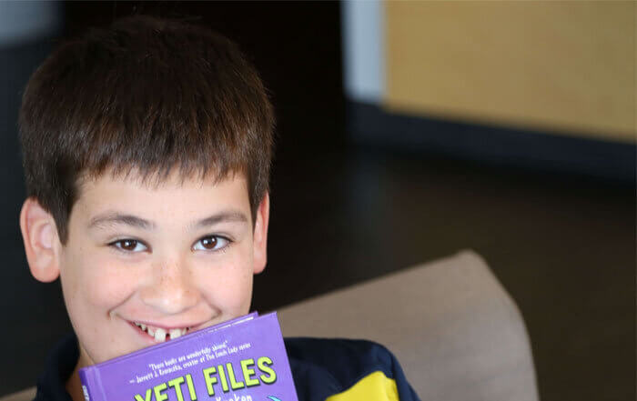 Boy with Yeti Files book, grinning