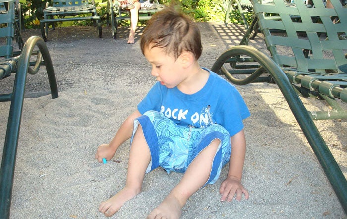 A boy with Fragile x syndrome playing in a sandbox.
