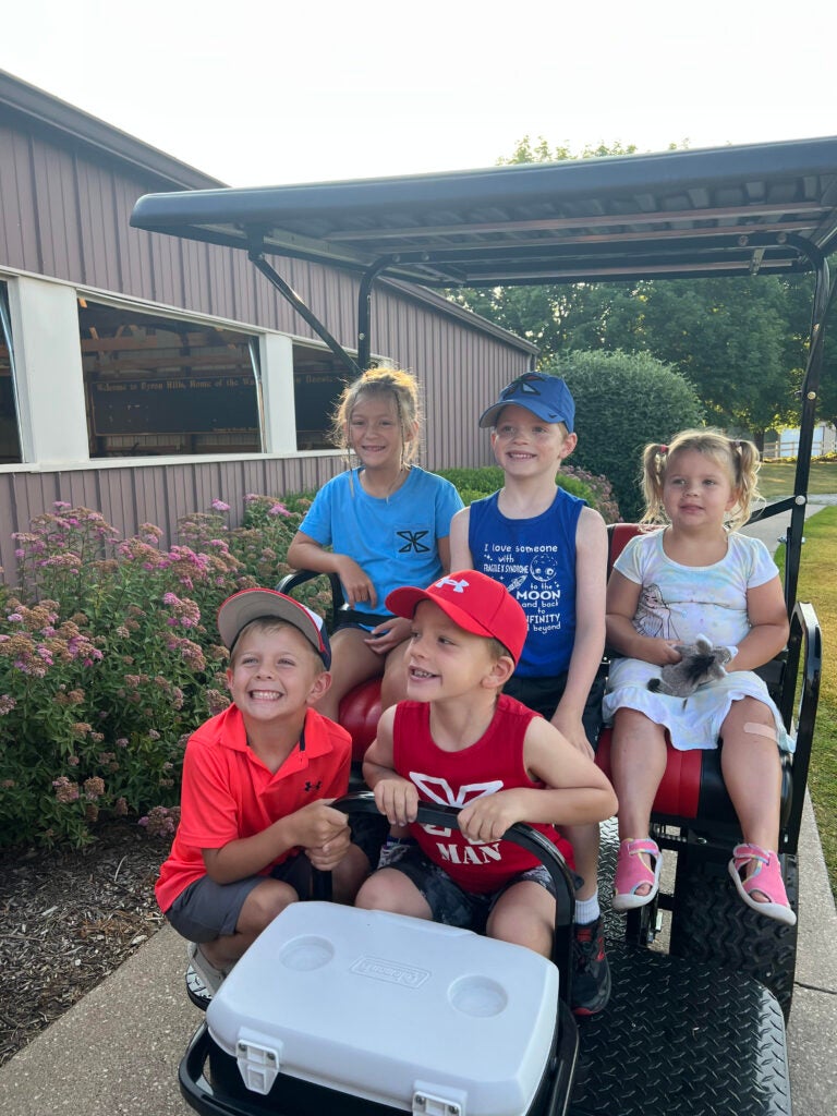A full load of kids on a golf cart.