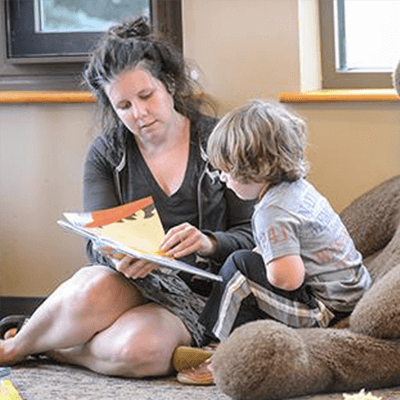 Woman and young boy sitting on the floor looking through book