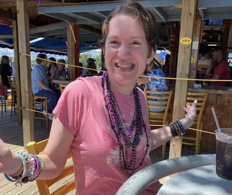 Courtney Laubach at an outdoor cafe, wearing lots of necklaces and bracelets, and smiling