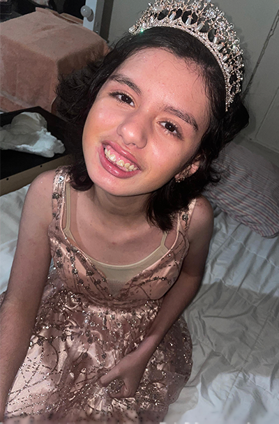 Denisse Parra Casarez smiling and wearing a sparkly tiara and pink satin dress.
