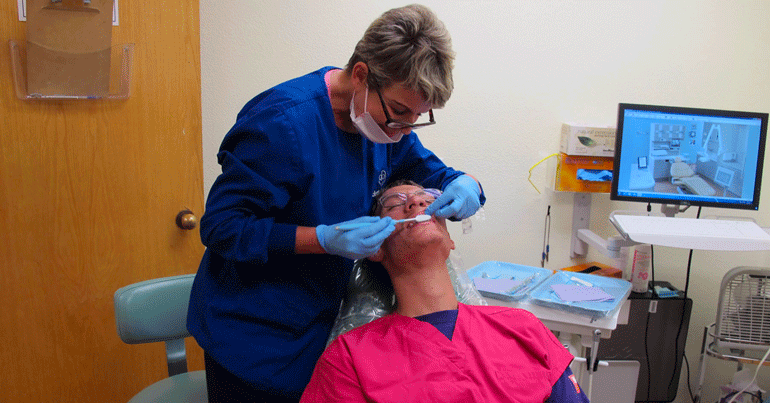 Ian, who has Fragile X syndrome, laying back in the dentist's chair while the dentist works on his teeth.