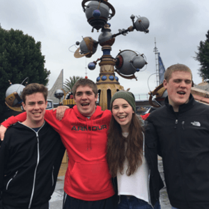 Teens near a fountain laughing side-by-side with their arms around each other