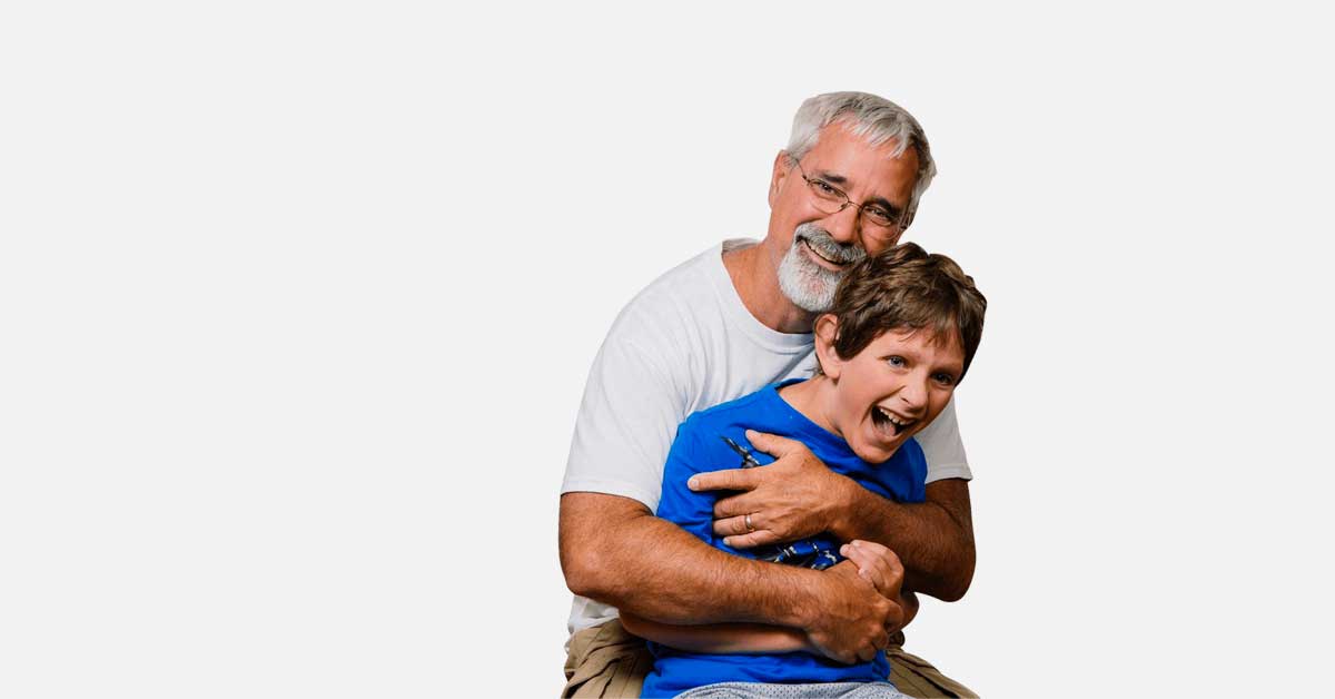 A father holding his son while both smile and laugh.