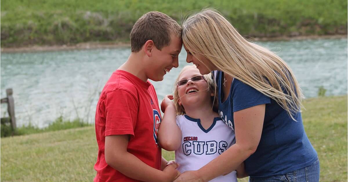 Parker, Allison and their mom Holly outdoors in loving embrace
