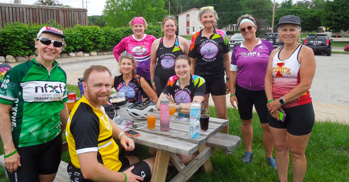 9 members of Bike to X Out Fragile X fundraiser take a break at a picnic table.