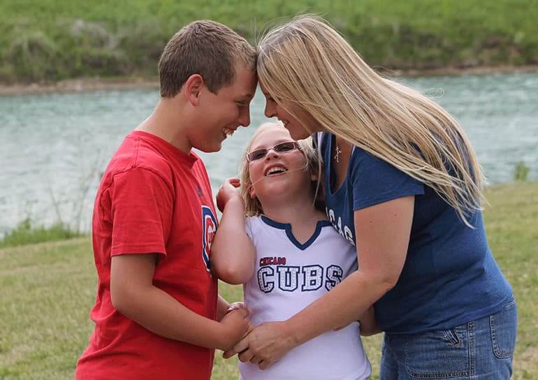 Holly with her son Parker and daughter Allison outdoors in a loving embrace