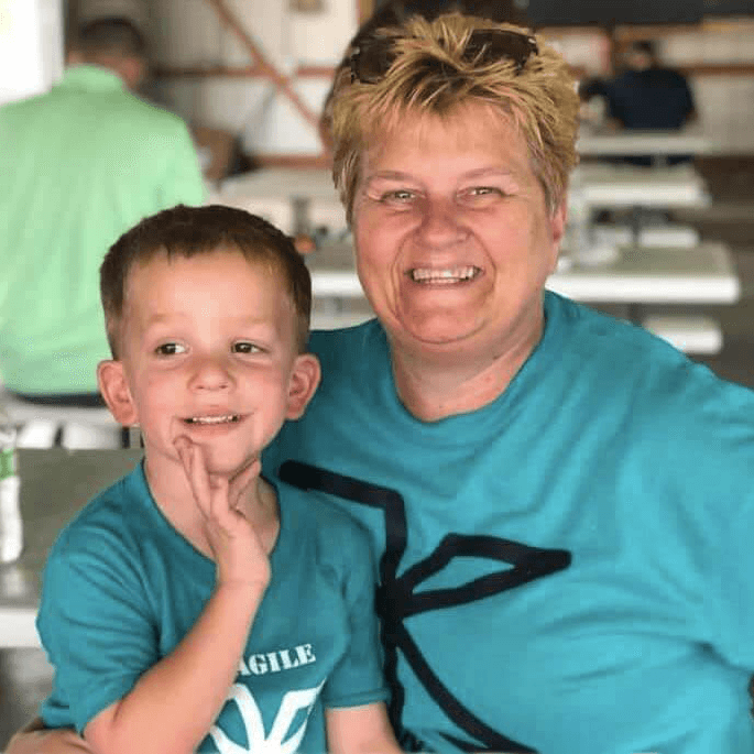 Woman with a young boy in her lap, wearing matching X logo t-shirts, and smiling