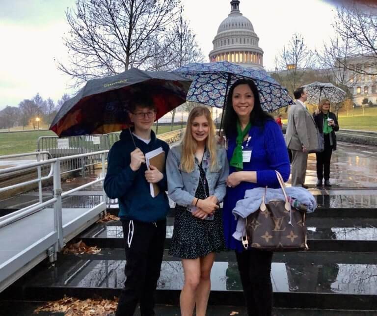 Jaden Randels and Kacie Coleman and Kelly in front of U.S. Capitol in the rain.