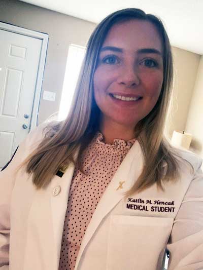 A young medical student, Kaitlin Hencak, wearing her lab coat and a pretty smile.