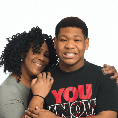 Mom with her arms around her son's shoulders, smiling.