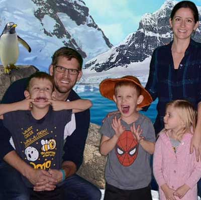 The Maderia family, including dad Arron and mom Jessica, two sons and a daughter, posing in front of a winter mountain backdrop.