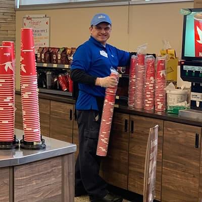 Man working at a convenience store stacking soda cups