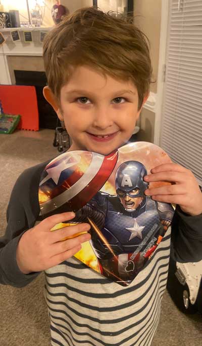 Miles David Tillman, a young boy with Fragile X syndrome, holding a superhero kevlar balloon.