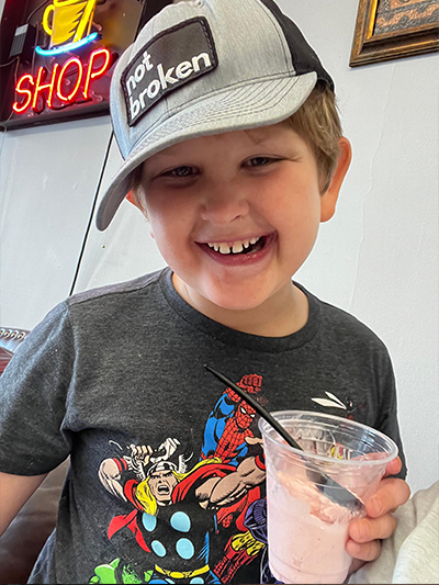 Miles Tillman wearing a "not broken" baseball cap and drinking a milkshake.