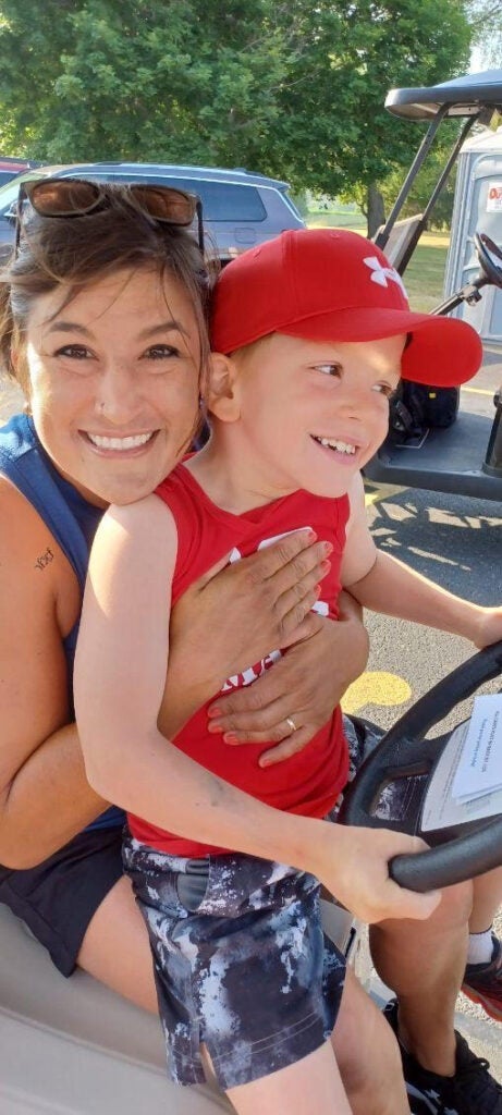 Mom and son smiling and having a great time on the golf course.