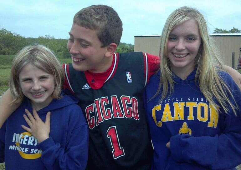 Two girls and a boy in the middle outdoors at school