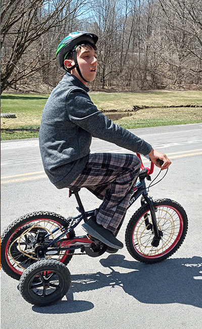 Phillip wearing a helmet and mastering his three-wheel bike.