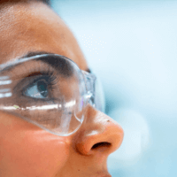 Woman in protective glasses looking forward and up